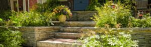 Front porch of a house in Lehigh Valley, featuring flourishing flower beds and vibrant planters along the steps, adding charm and color to the entrance.